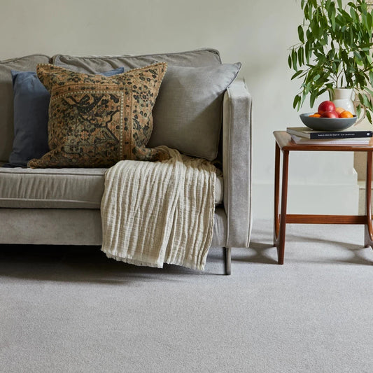 Gray sofa with decorative pillows and a blanket in a living room setting.