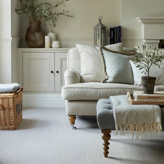Cozy living room with a beige sofa, ottoman, and decorative items.